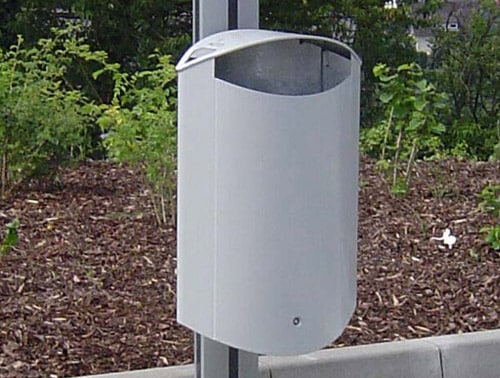 Ein Abfallbehälter aus Stahl, der an einem Pfosten befestigt ist