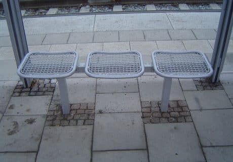 Graue Drahtgittersitze in einer Wartehalle