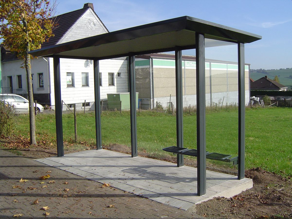 Eine graue dreifeldrige Wartehalle einschließlich Betonbodenplatte und Plattendekor-Oberfläche