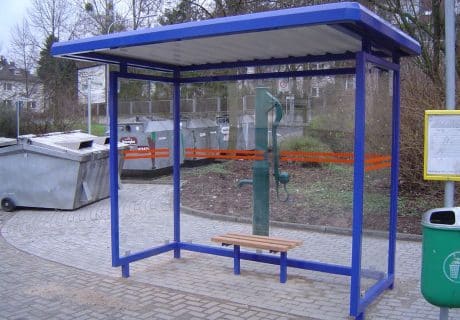 Eine dunkelblaue zweifeldrige Wartehalle neben Müllcontainern