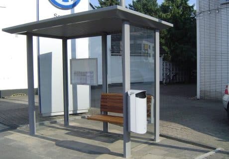 Eine graue zweifeldrige Wartehalle einschließlich Abfallbehälter sowie Sitzbank