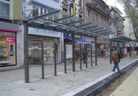 Eine Fahrradüberdachung am Straßenrand vor mehreren Geschäften