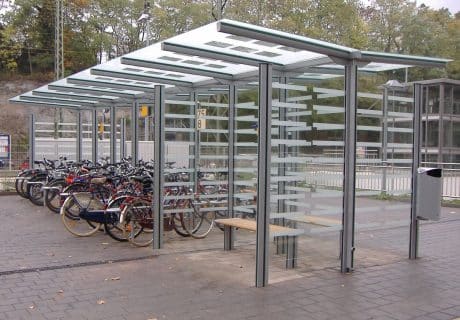 Eine graue achtfeldrige Wartehalle mit Sitzbank und mehreren Fahrradanlehnbügeln