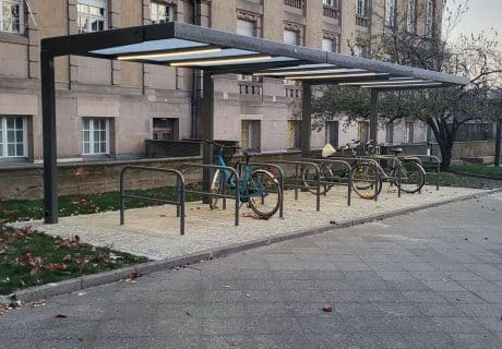 Eine Fahrradüberdachung mit mehreren Fahrradanlehnbügeln vor einem Schloss