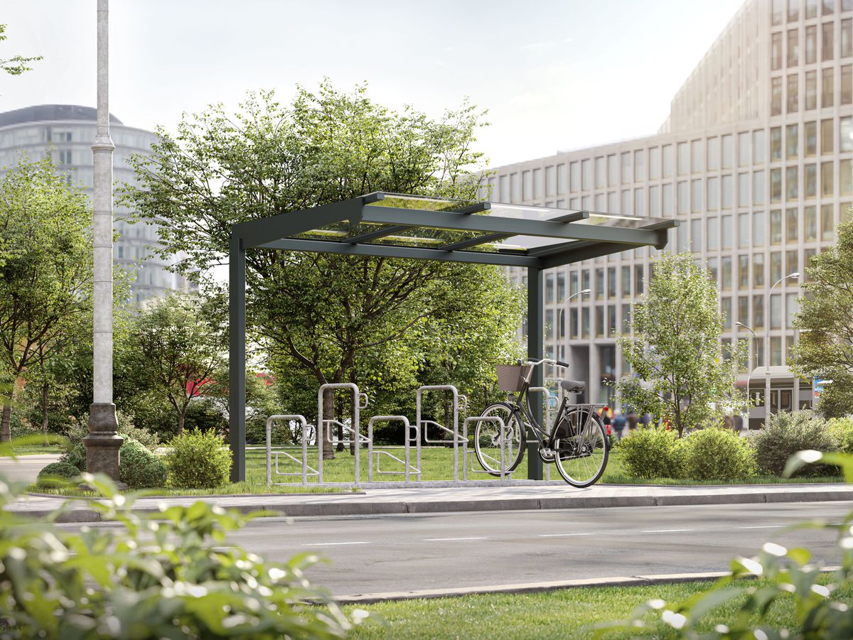 Eine Fahrradüberdachung mit mehreren Fahrradbügeln vor einer Wiese