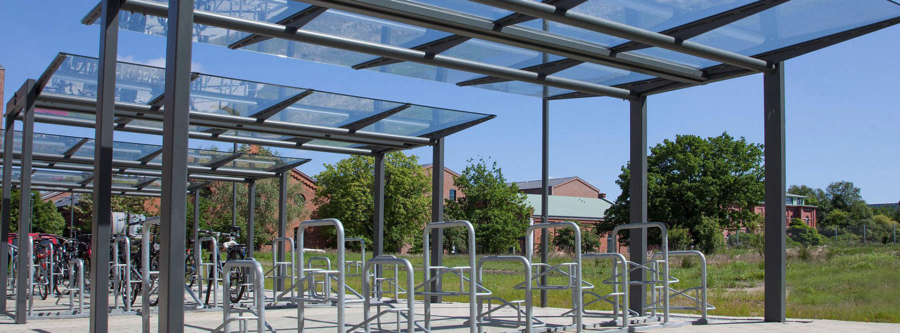 Vier Fahrradüberdachungen mit mehreren Fahrradbügeln