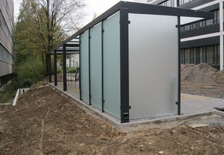 Eine Fahrradüberdachung mit mehreren Fahrradbügeln und undurchsichtigen Scheiben