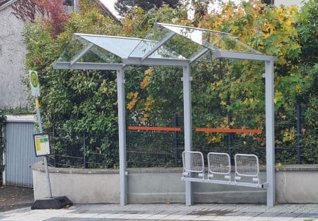 Eine graue zweifeldrige Wartehalle mit Klappsitzen am Straßenrand