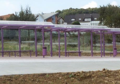 Eine lilafarbene an die Gefällelage angepasste Wartehalle am Straßenrand