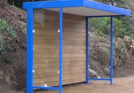 Eine Wartehalle mit Holzrückwand am Wegesrand