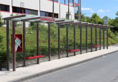 Eine graue zwölffeldrige Wartehalle am Straßenrand mit der Aufschrift "Adolf-Reichwein-Straße"