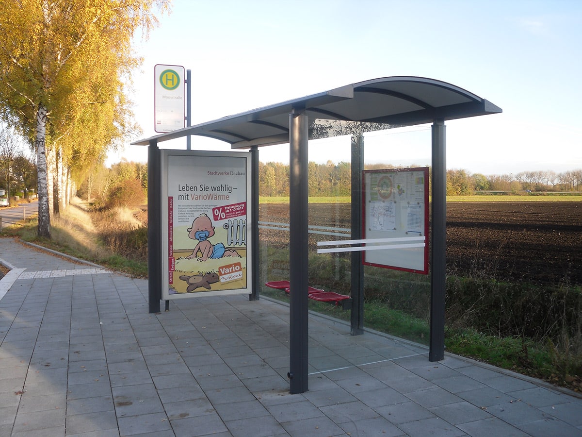 Eine graue Wartehalle mit Werbevitrine am Wegesrand
