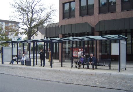 Eine schwarze zwölffeldrige Wartehalle mit vielen Personen und einem Durchgang in der Mitte