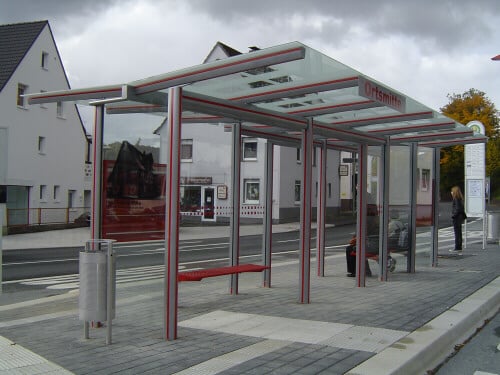 Eine Wartehalle mit trapezförmigem, doppelseitig auskragendem Dach mit der Aufschrift "Ortsmitte"