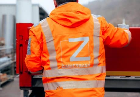 Mitarbeiter mit orangener Warnweste auf der das Logo von Zimmermann Stadtmöblierung zu sehen ist